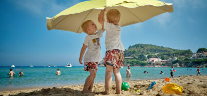 2 boys on a beach under yellow umbrella